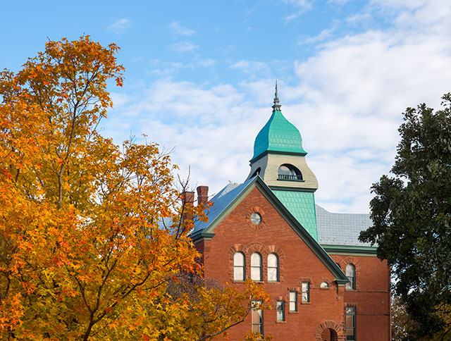 A tree with gold and red autumn leaves stands beside Old Central.