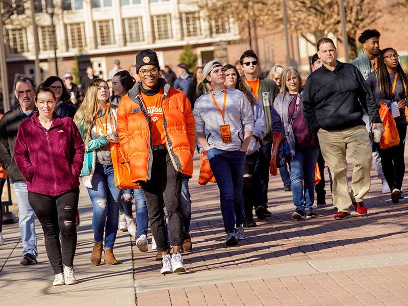 A tour guide smiles as he leads a group of prospective students and their families across campus on Admitted Student Day.